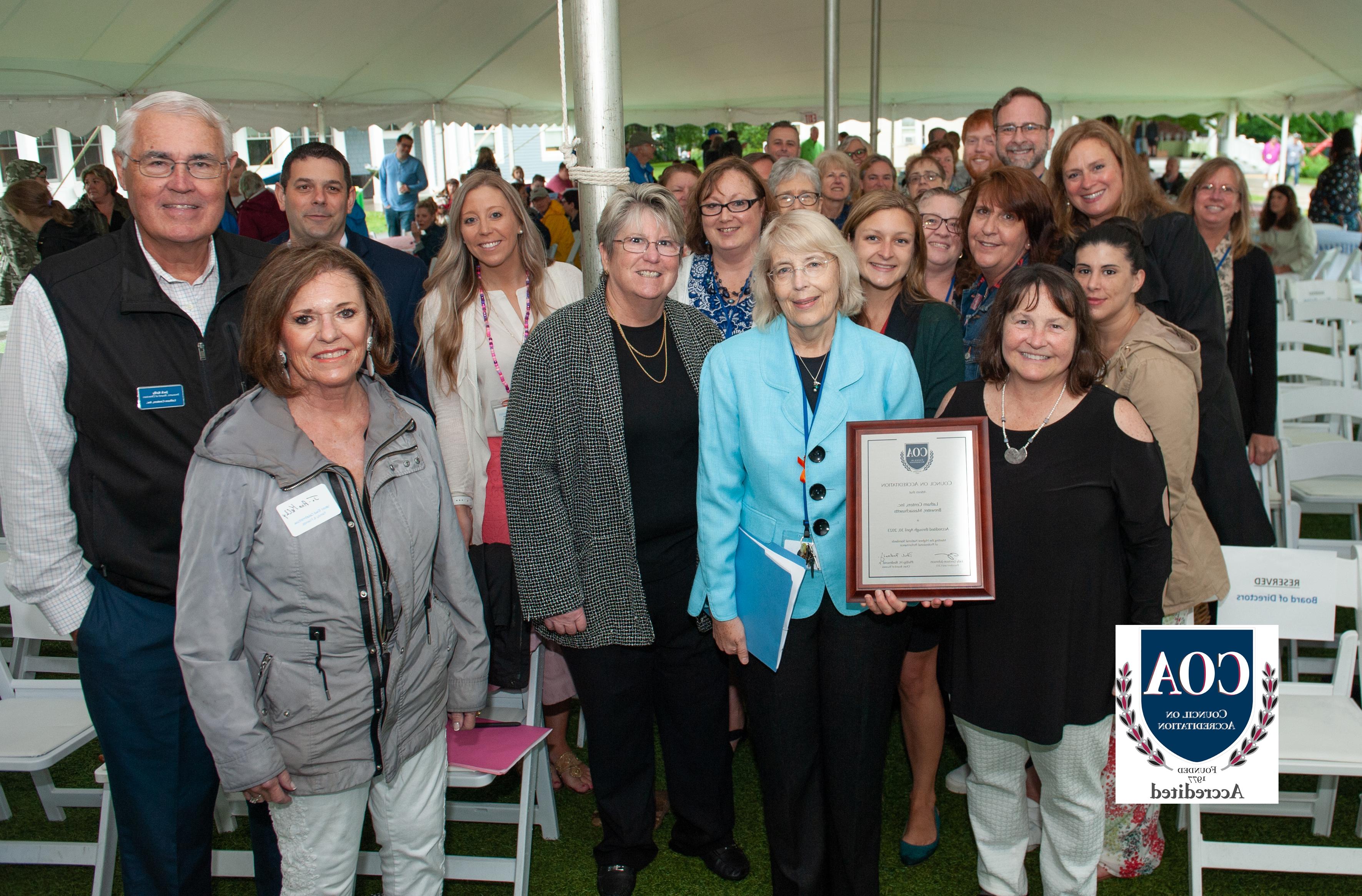 Latham staff, family, 和 friends hold up COA plaque at End of Year Celebration